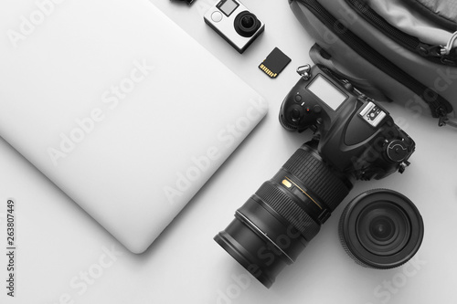 Modern equipment of professional photographer with laptop on light background