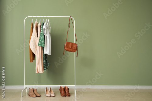 Rack with stylish clothes near color wall