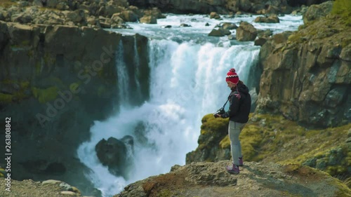 Woman standing on cliff rock at Fossardalur waterfall, Iceland photo