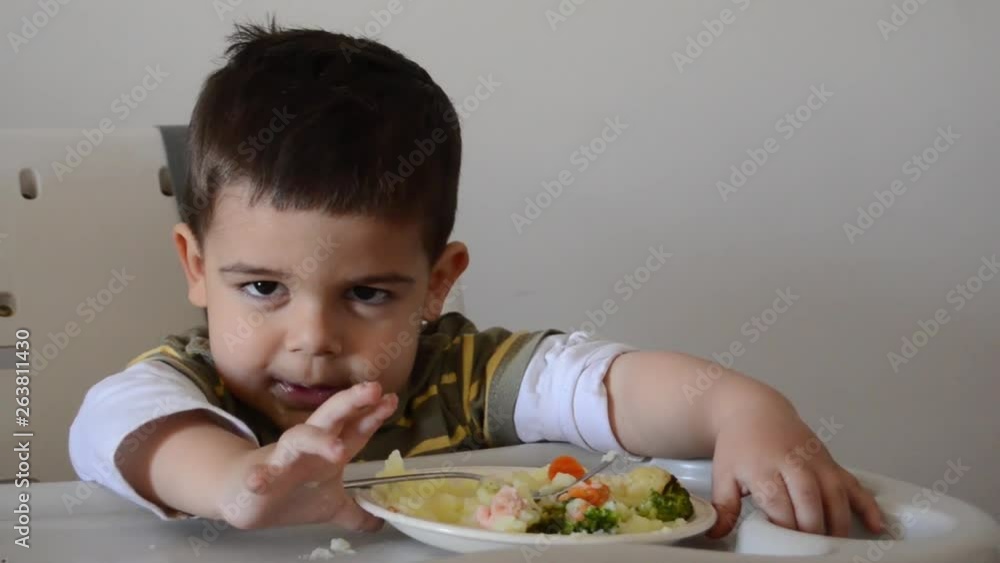 Grumpy two years old boy playing with food and refusing to eat. Grumpy two years old boy playing with food and refusing to eat.