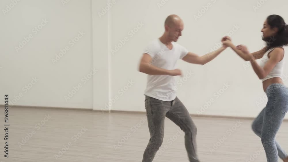 Gorgeous woman wearing heels dancing with a man in a dance studio. Gorgeous woman wearing heels dancing with a man in a dance studio.