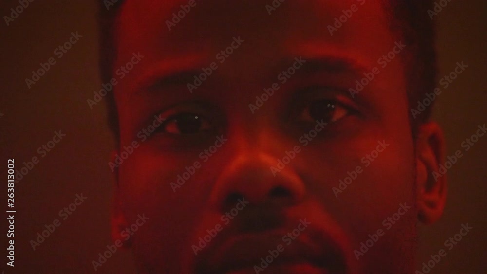 Close up of African American mans face while still with flashing colorful lights Close up of African American mans face while still with flashing colorful lights