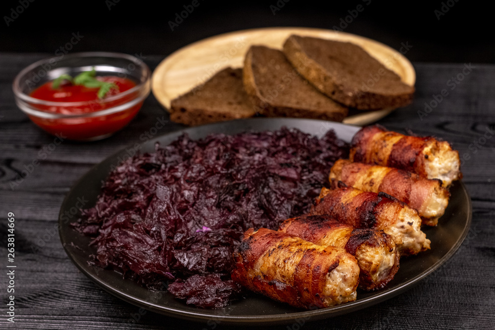Fried homemade grilled sausages or chevapchichi with stewed sauerkraut, and slices of rye bread and tomato sauce on a wooden rustic background Fried homemade grilled sausages or chevapchichi with stewed sauerkraut, and slices of rye bread and tomato sauce on a wooden rustic background