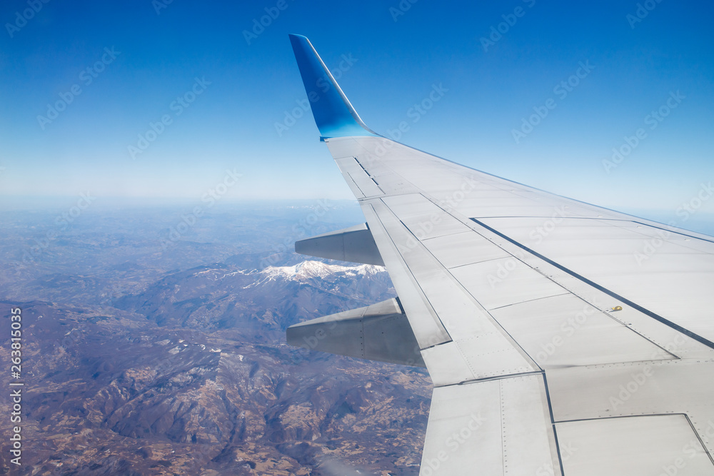 Photo from window of wing airplane flying over Alps mountains. Travel concept