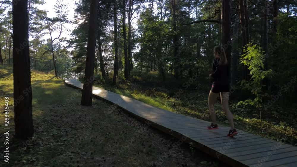 Caucasian woman running through a forest on a wooden path Caucasian woman running through a forest on a wooden path