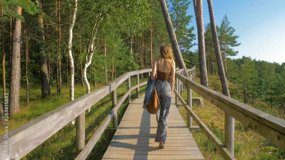 Caucasian woman walking away through a path in the forest Caucasian woman walking away through a path in the forest