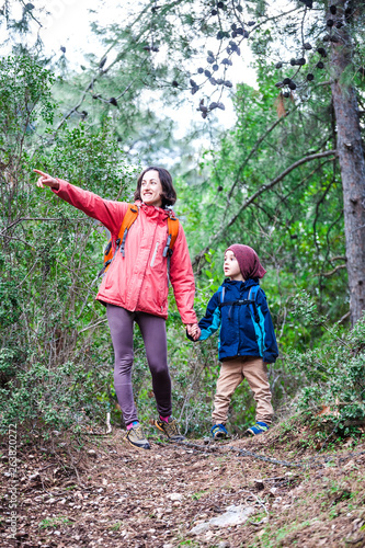 A woman walks with her son through the forest.