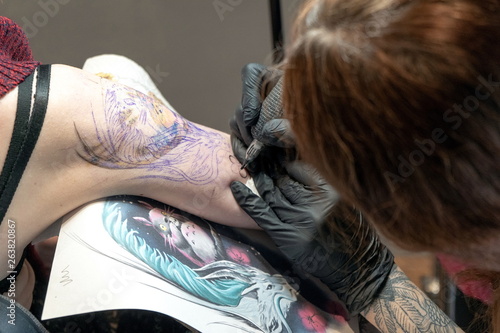 Tattoo master makes a client a colorful tattoo