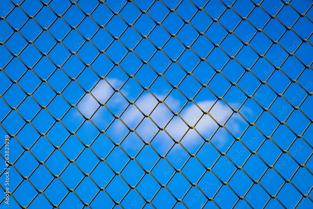 iron fence on a blue sky with clouds, Mesh fence with partly cloudy sky, Chain link fence and a blue sky, metal fence and Blue sky background beyond iron fence on a blue sky with clouds, Mesh fence with partly cloudy sky, Chain link fence and a blue sky, metal fence and Blue sky background beyond