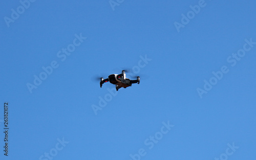 drone quadcopter with digital camera, drone hovering in a bright blue sky