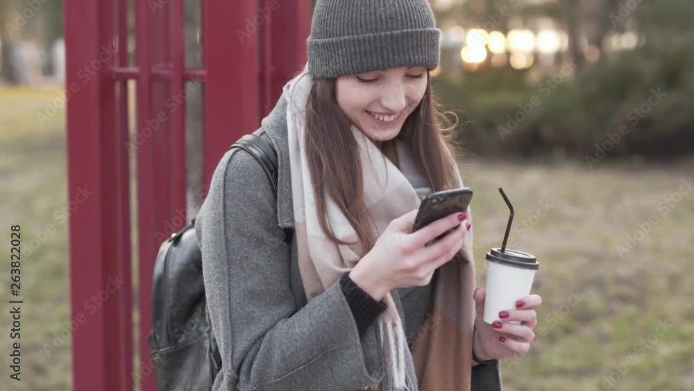 Woman sitting at the park while laughing and looking at her cell phone Woman sitting at the park while laughing and looking at her cell phone