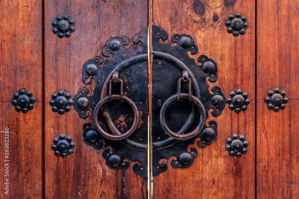 Korean wooden door panels decorated with old black metallic ring handles at a house in ancient village in Jeonju, South Korea Korean wooden door panels decorated with old black metallic ring handles at a house in ancient village in Jeonju, South Korea