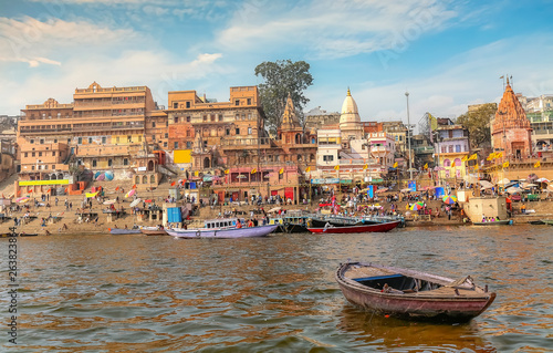 Ancient Varanasi city architecture with view of a wooden boat on river Ganges at sunset
