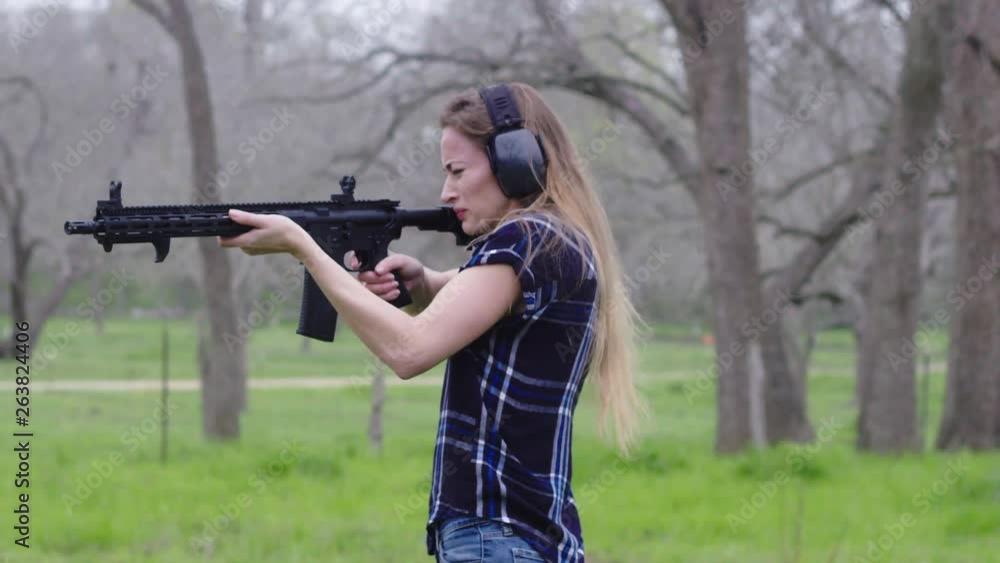 Side view of a woman aiming and firing at a target during shooting practice, slow motion 24 fps. Side view of a woman aiming and firing at a target during shooting practice, slow motion 24 fps.