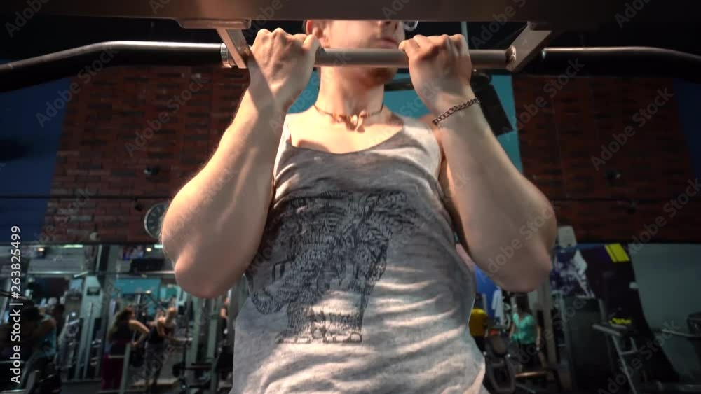 Closeup of young muscular man does pull-ups on a bar in an indoor gym. Closeup of young muscular man does pull-ups on a bar in an indoor gym.
