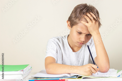 Sad boy doing homework. Education, school, learning difficulties concept photo