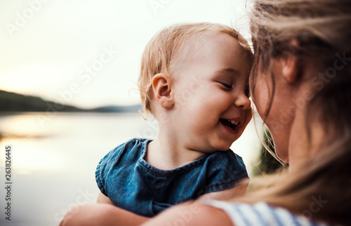 Leinwand Poster Smiling mother holding toddler outdoors