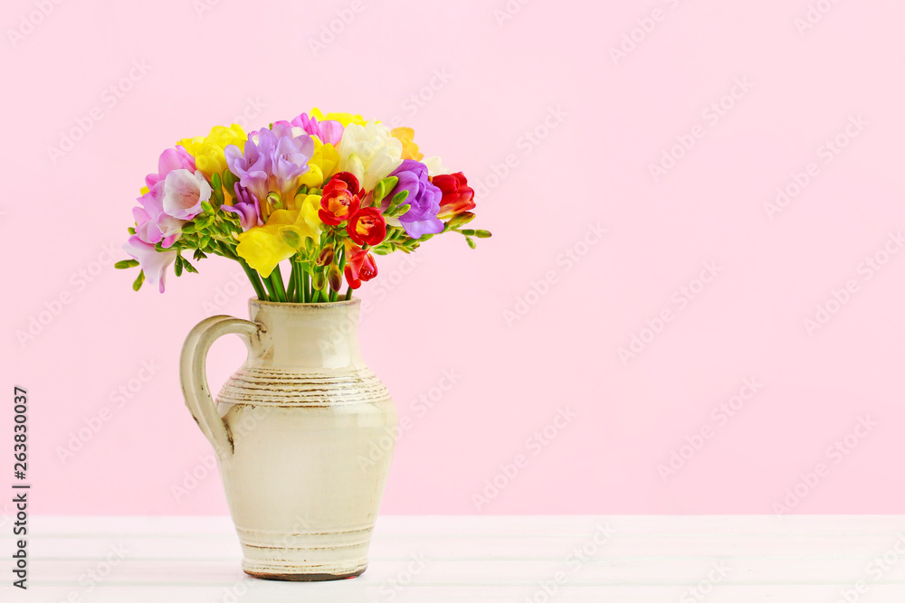 Bouquet of colorful freesia flowers in ceramic jug