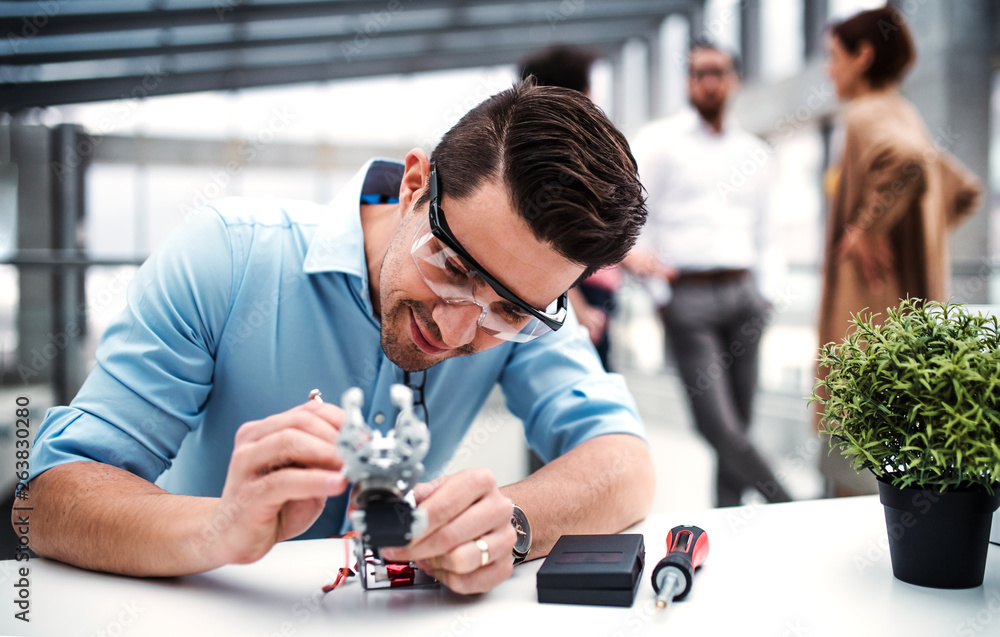 Samolepka A young businessman or scientist with robotic hand standing in office, working
