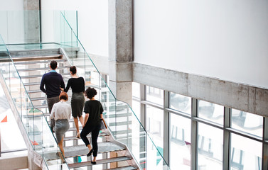 Rear view of group of young businesspeople walking up the stairs.