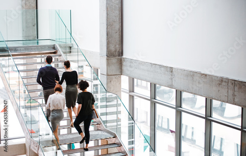 Foto Rear view of group of young businesspeople walking up the stairs.