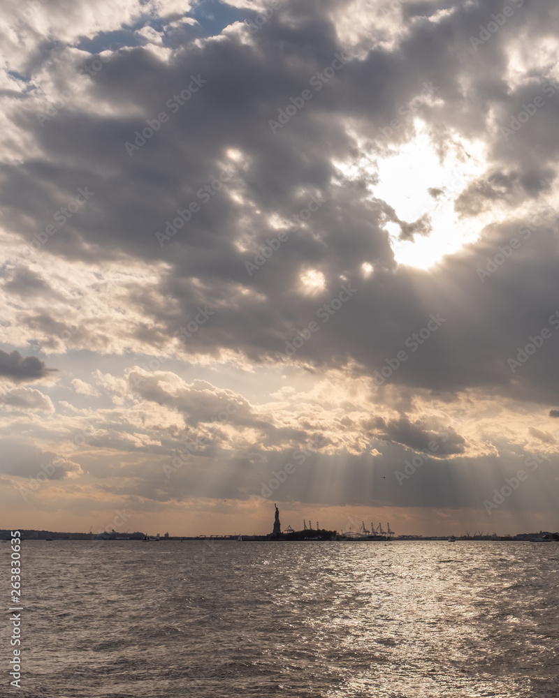 Statue of Liberty over water at Sunset, in New York City, USA