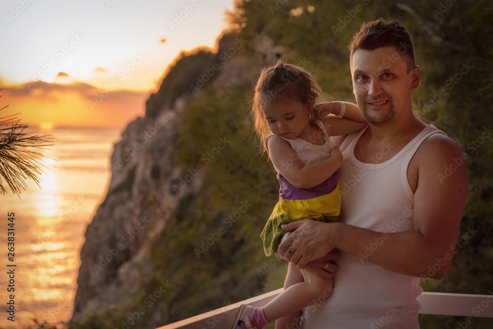 Dad holds the baby in his arms against the mountains and sunset. The concept of raising a father of young children, travel Dad holds the baby in his arms against the mountains and sunset. The concept of raising a father of young children, travel