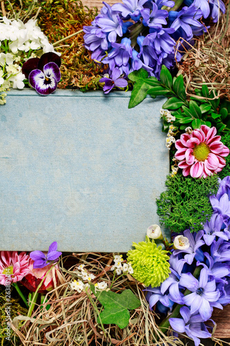 Old book among spring flowers, copy space.