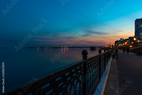 Spring night city quay embankment under sunset. Street decorative lights and beautiful sky