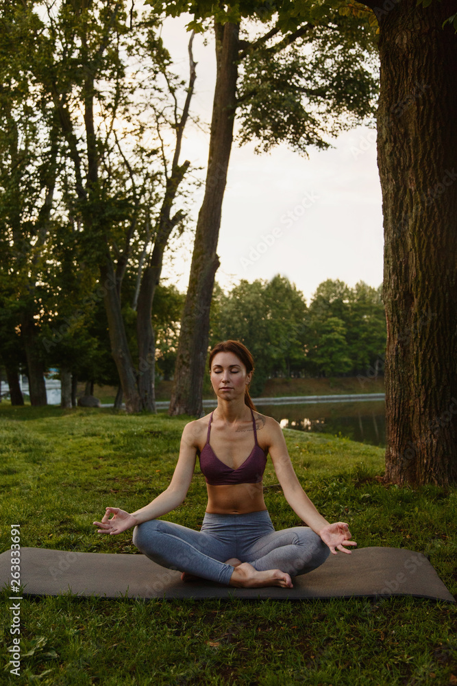 Woman sitting and meditating in green park Woman sitting and meditating in green park