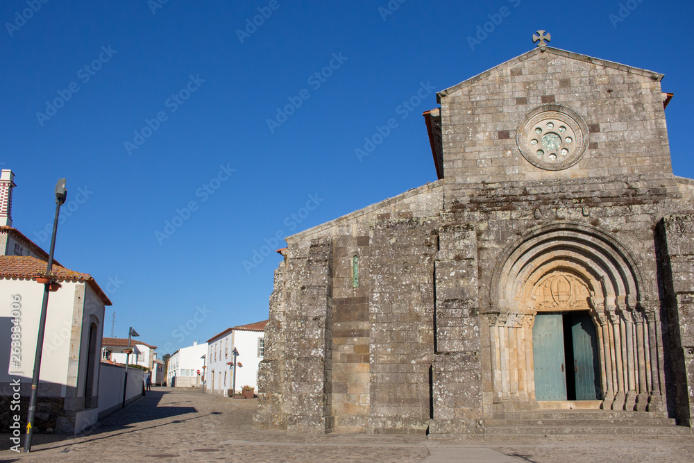 Ancient church in medieval village in Spain. Old stone church with open entrance. Catholic cathedral on clear blue sky background. Facade of historical building. Religious architecture.  