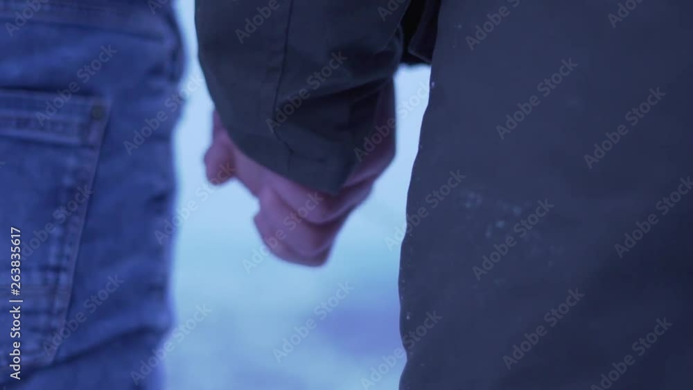Close up back shot in winter setting of a female standing, which is then approached and taken by hand by a man Close up back shot in winter setting of a female standing, which is then approached and taken by hand by a man