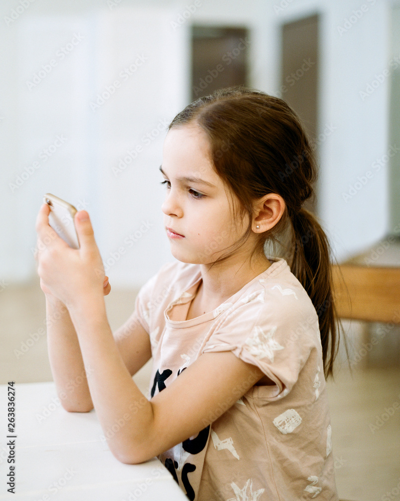 Girl browsing smartphone in kitchen Girl browsing smartphone in kitchen