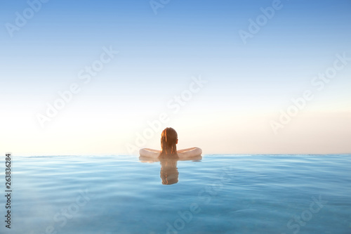 Woman relaxing in infinity swimming pool on vacation