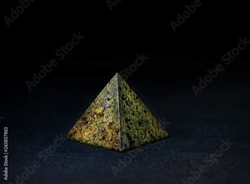 mineral serpentine in shape of pyramid. natural mineral stone serpentine (Serpentinite) on dark background. Serpentine is stone used for protecting, preserving beliefs, calming spirit. meditation aids photo