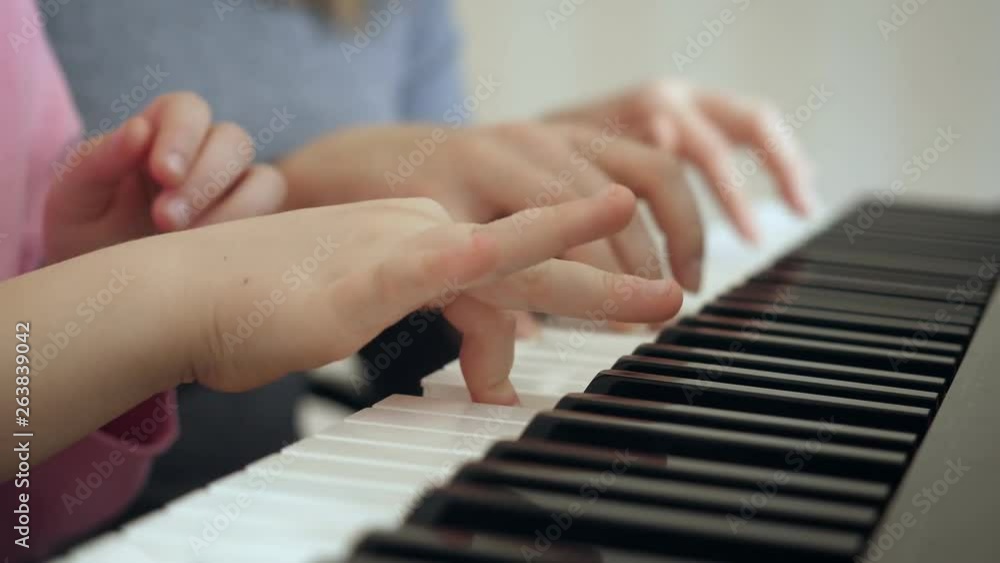 Young woman teaches little girl to play the piano. Young woman teaches little girl to play the piano.