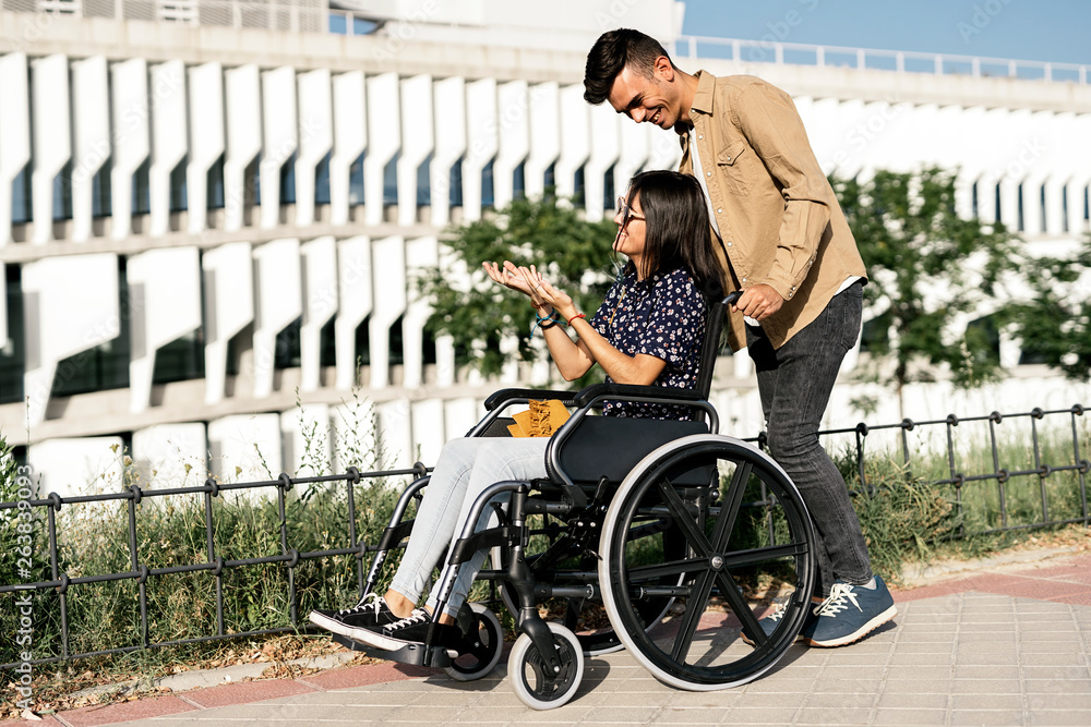 Young woman sitting on a wheelchair and her boyfriend walking Stock ...