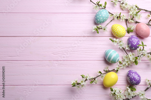 Flat lay composition with painted Easter eggs and blossoming branches on wooden background. Space for text © New Africa