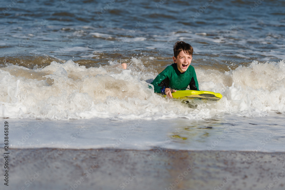 Boy wearing wetsuit learns how to bodyboard in the English sea Boy wearing wetsuit learns how to bodyboard in the English sea