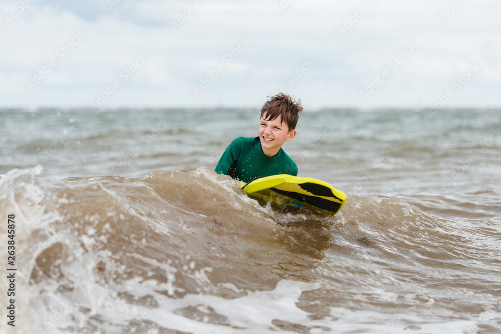 Boy wearing wetsuit learns how to bodyboard in the English sea Boy wearing wetsuit learns how to bodyboard in the English sea