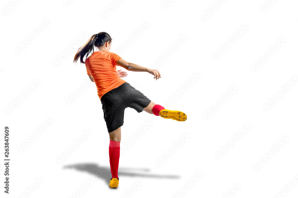 Rear view of asian football player woman in orange jersey with kicking the ball Rear view of asian football player woman in orange jersey with kicking the ball