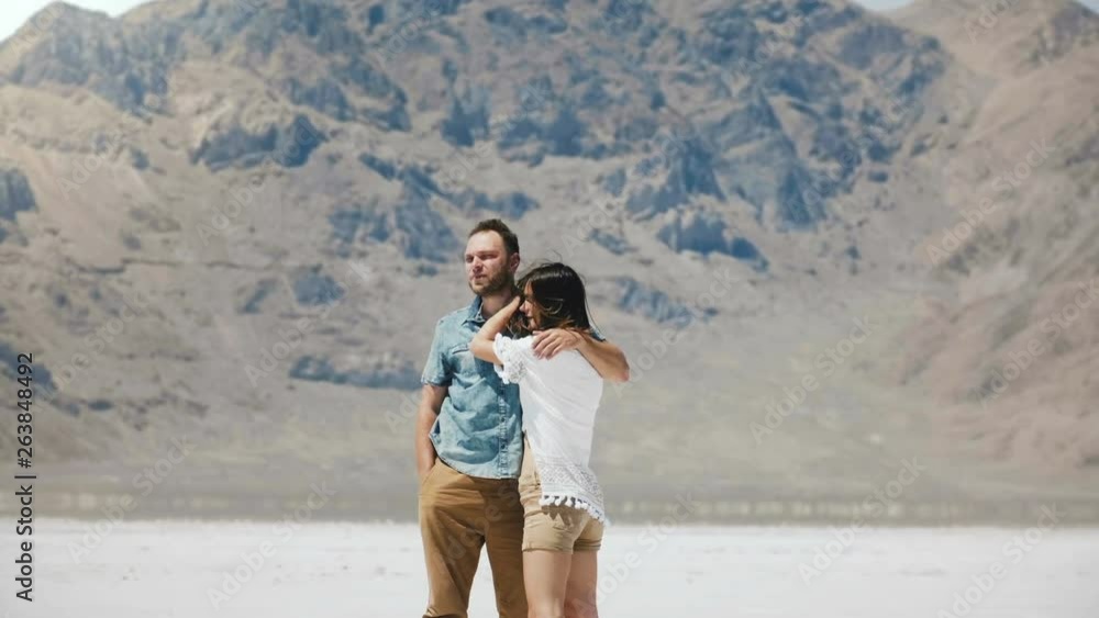 Happy attractive romantic couple stand together hugging, kissing at epic white flat salt desert of Bonneville Utah. Happy attractive romantic couple stand together hugging, kissing at epic white flat salt desert of Bonneville Utah.