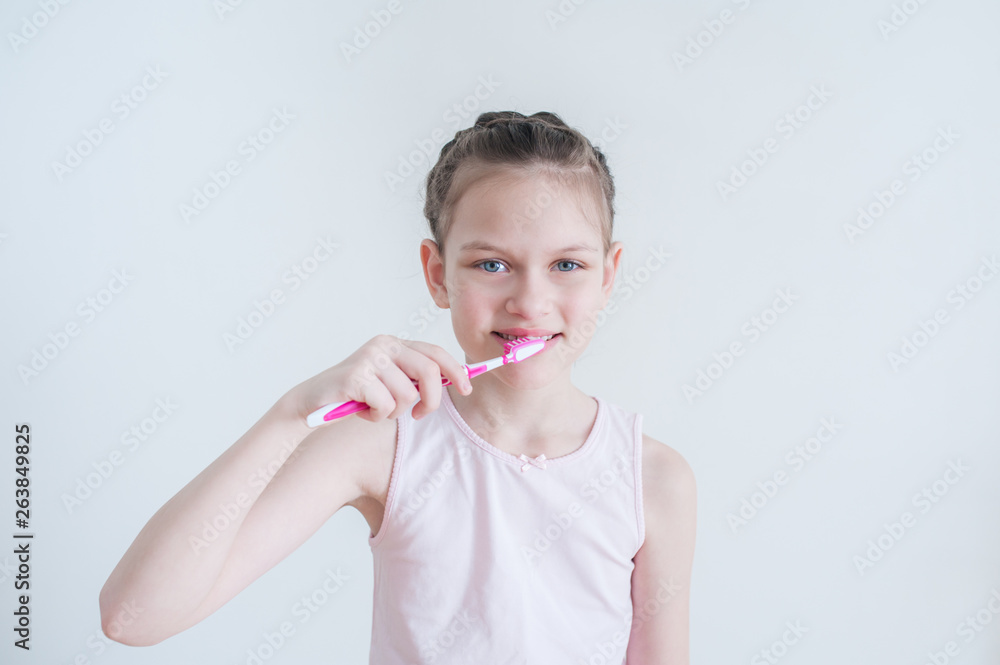 Cheerful cute girl brushes her teeth with a pink brush Cheerful cute girl brushes her teeth with a pink brush