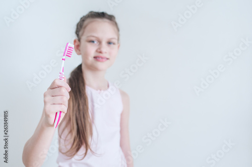Cheerful cute girl brushes her teeth with a pink brush
