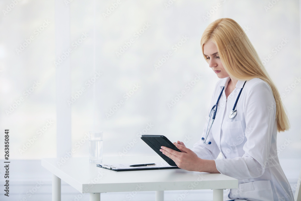 Female caucasian doctor using tablet and writing diagnosis in medical forms documents Female caucasian doctor using tablet and writing diagnosis in medical forms documents
