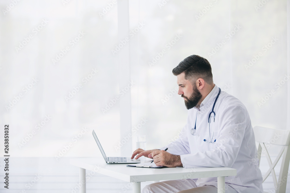 Doctor is working with documents and laptop in his medical office Doctor is working with documents and laptop in his medical office