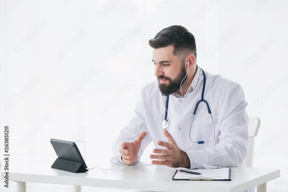 Sincere doctor is looking at camera of pc tablet and giving positive encouragement Sincere doctor is looking at camera of pc tablet and giving positive encouragement