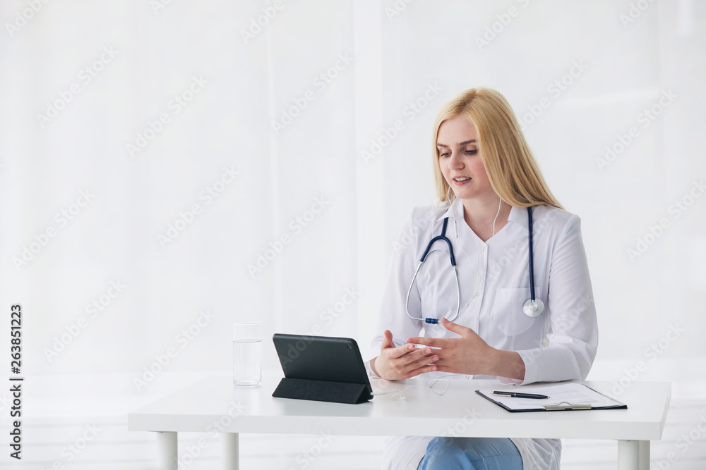 Sincere doctor is looking at camera of pc tablet and giving positive encouragement Sincere doctor is looking at camera of pc tablet and giving positive encouragement