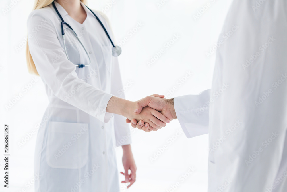 Doctors in lab coats greeting each other with handshake Doctors in lab coats greeting each other with handshake