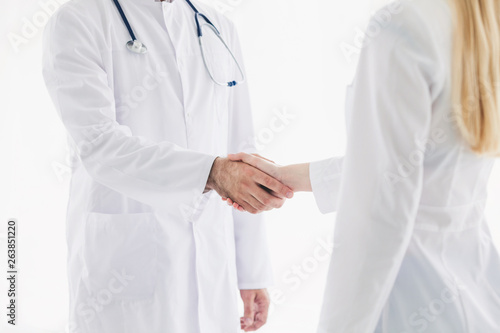 Doctors in lab coats greeting each other with handshake 